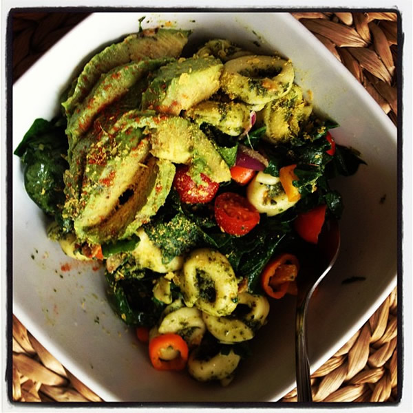 Some clean eating - Wilted garlic spinach, topped with pesto tortellini, baby bell peppers, grape tomatoes, shallots, sliced avocado with a pinch of cayenne and nutritional yeast